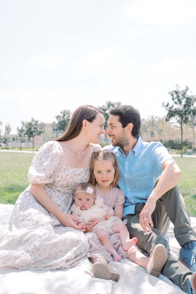 a man and woman sitting on a blanket with a baby