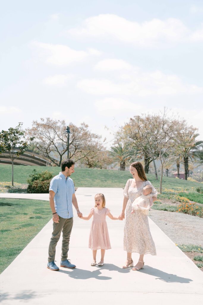 family holding hands at newborn photo session in San Diego