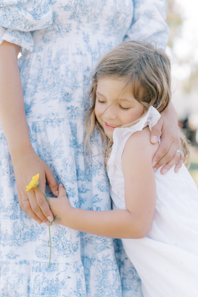 a girl holding a flower and hugging her mother