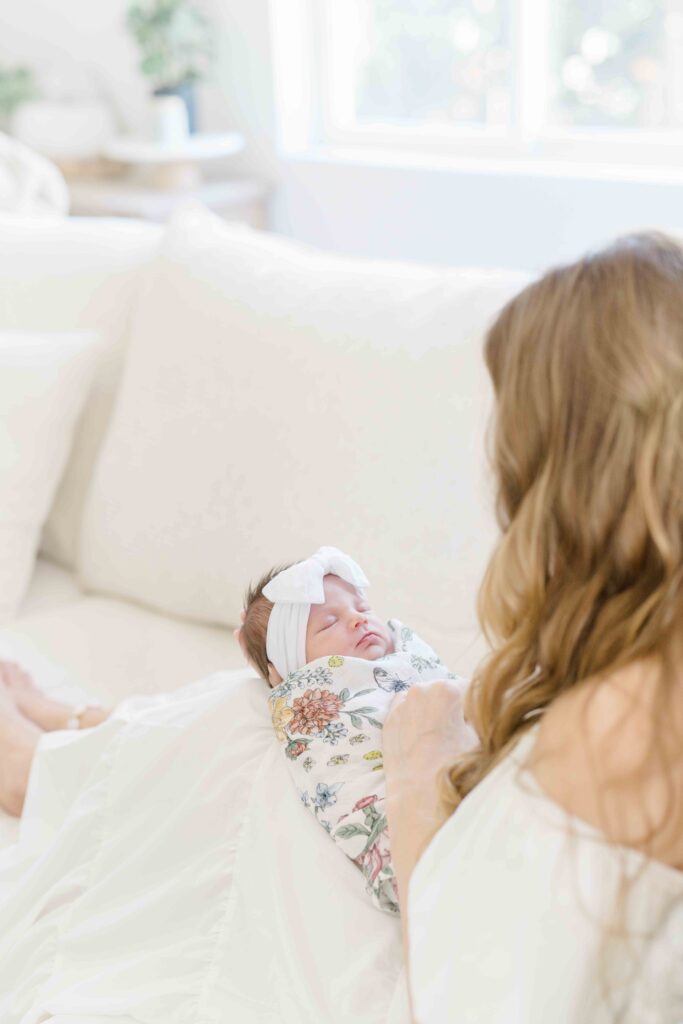 mom with sleeping newborn in their beautiful living room