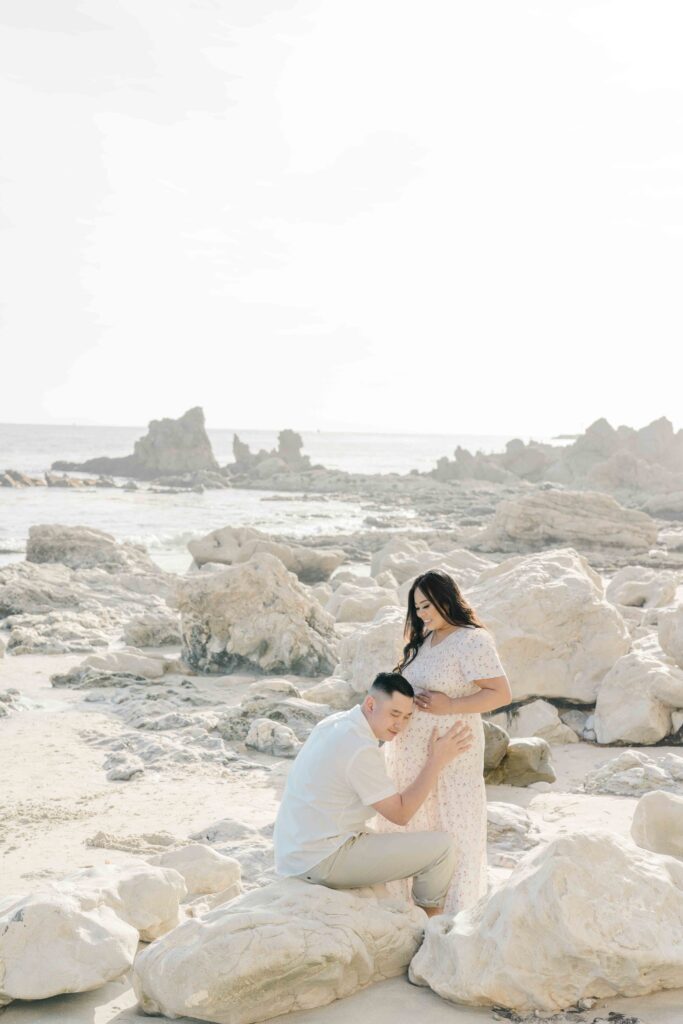 beautiful beach view of parents posing for maternity session in san diego