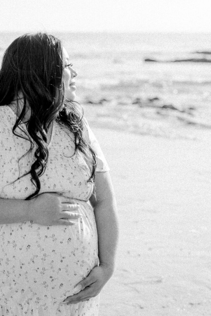 beach maternity session with mom looking into the ocean